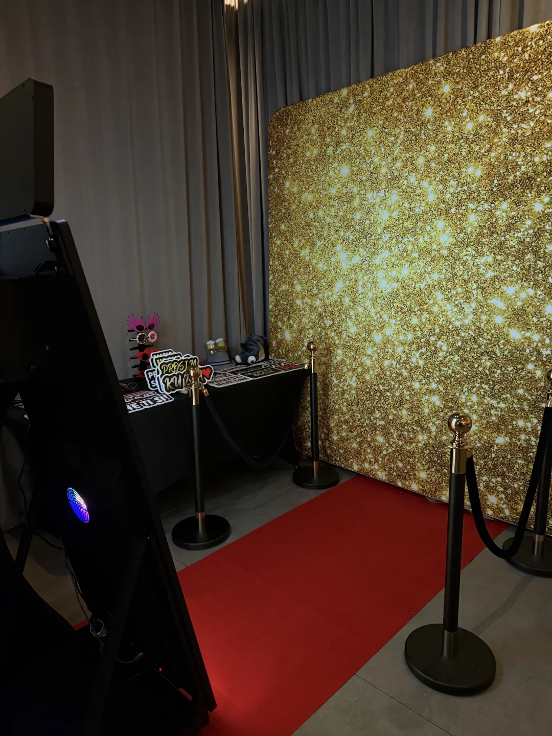 Photobooth kutak sa zlatnom svjetlucavom pozadinom, crvenim tepihom, VIP ogradom i rekvizitima