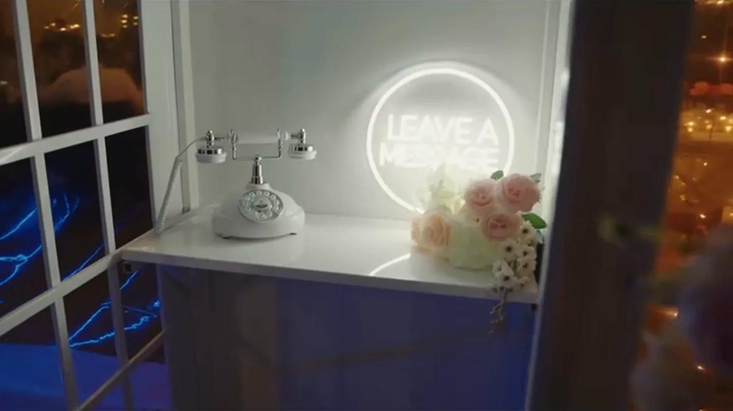 Bijeli starinski telefon ispod svjetlećeg natpisa Leave a message
